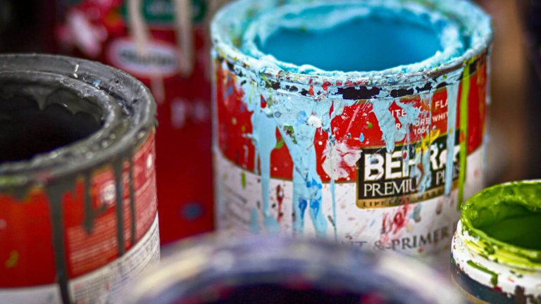 Open verfblikken met blauwe, groene en grijze verf, met spatten en druipers langs de randen.