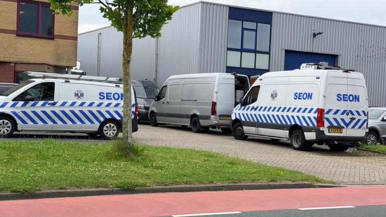 Drie SEON bestelbussen en een witte bestelbus geparkeerd bij industriële gebouwen.