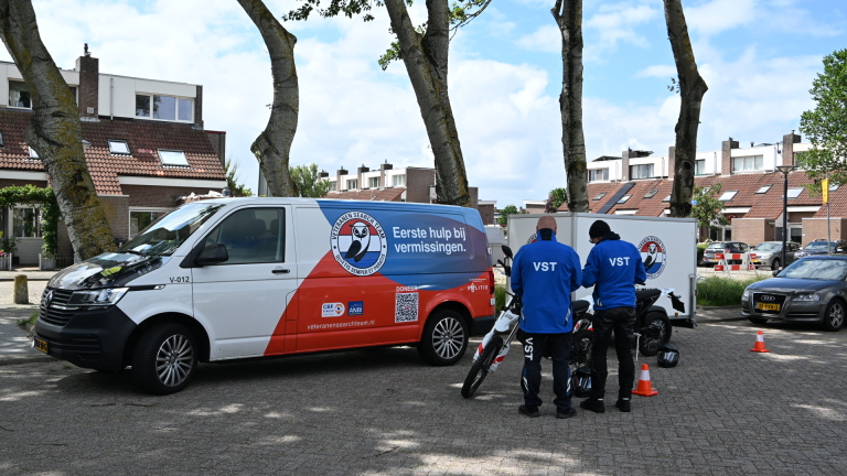 Busje van Veteranen Search Team met opschrift "Eerste hulp bij vermissingen" en twee personen in VST-kleding naast een motor.