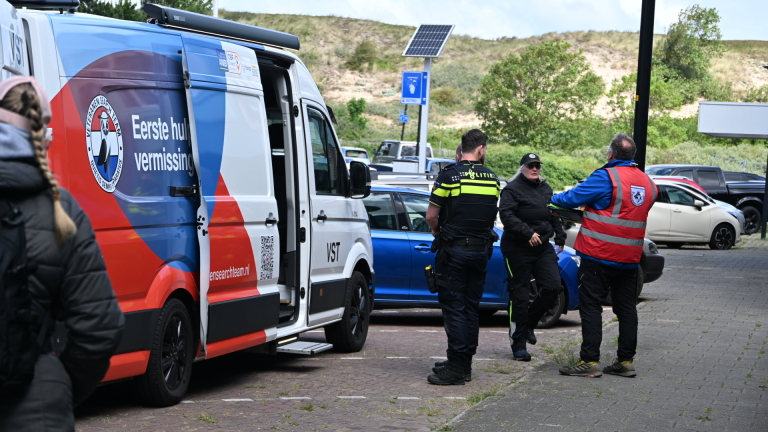 Hulpverleners en politie overleggen bij een bus van het Veteranen Search Team met opschrift "Eerste hulp vermissing".
