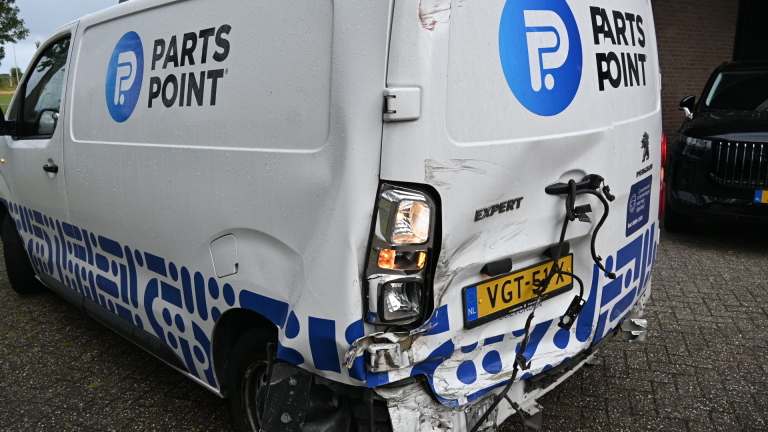 Beschadigde witte PartsPoint-bestelbus met gedeukte achterdeur, loshangende kabels en kapotte achterbumper