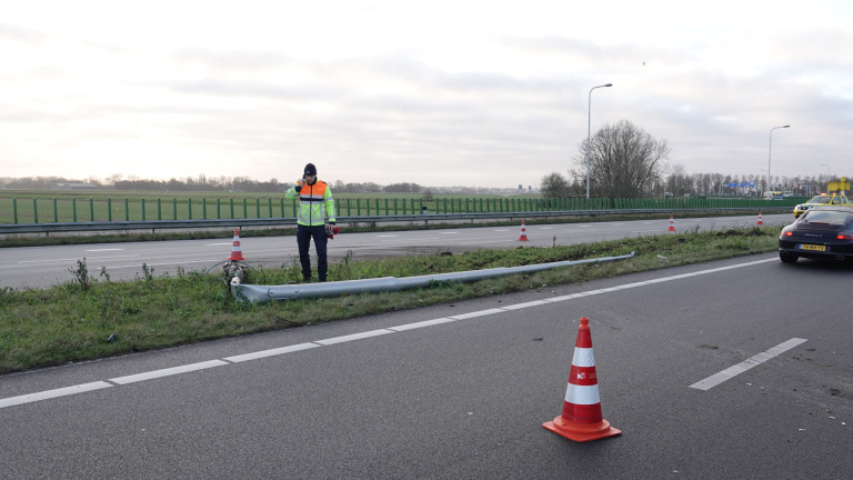 Auto met zware schade aan de voorkant na een verkeersongeval, met sleepwagen en omstanders op de achtergrond.