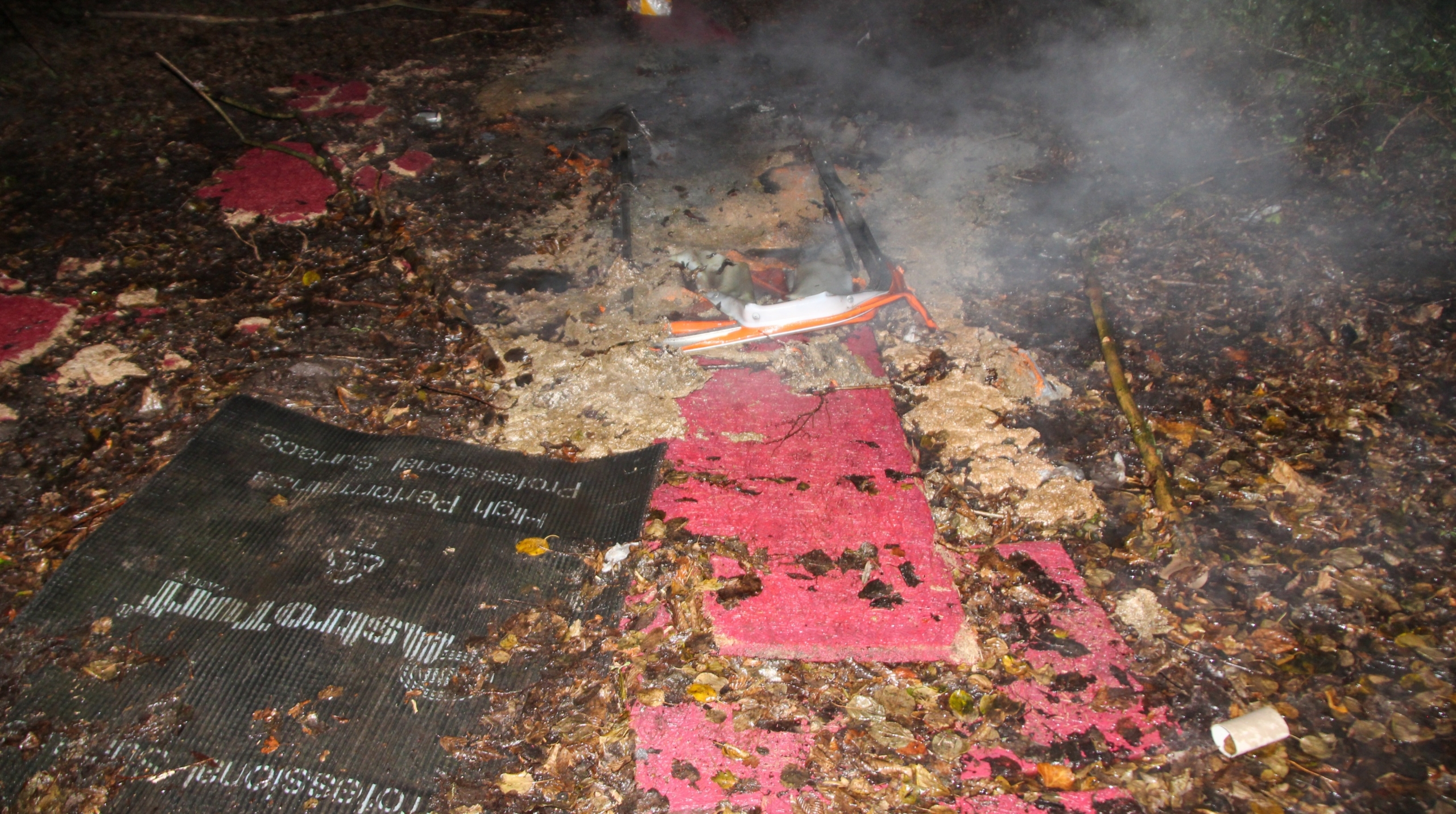 Brandweermannen in uniform bestrijden 's nachts een felle brand bij een omheind gebied.