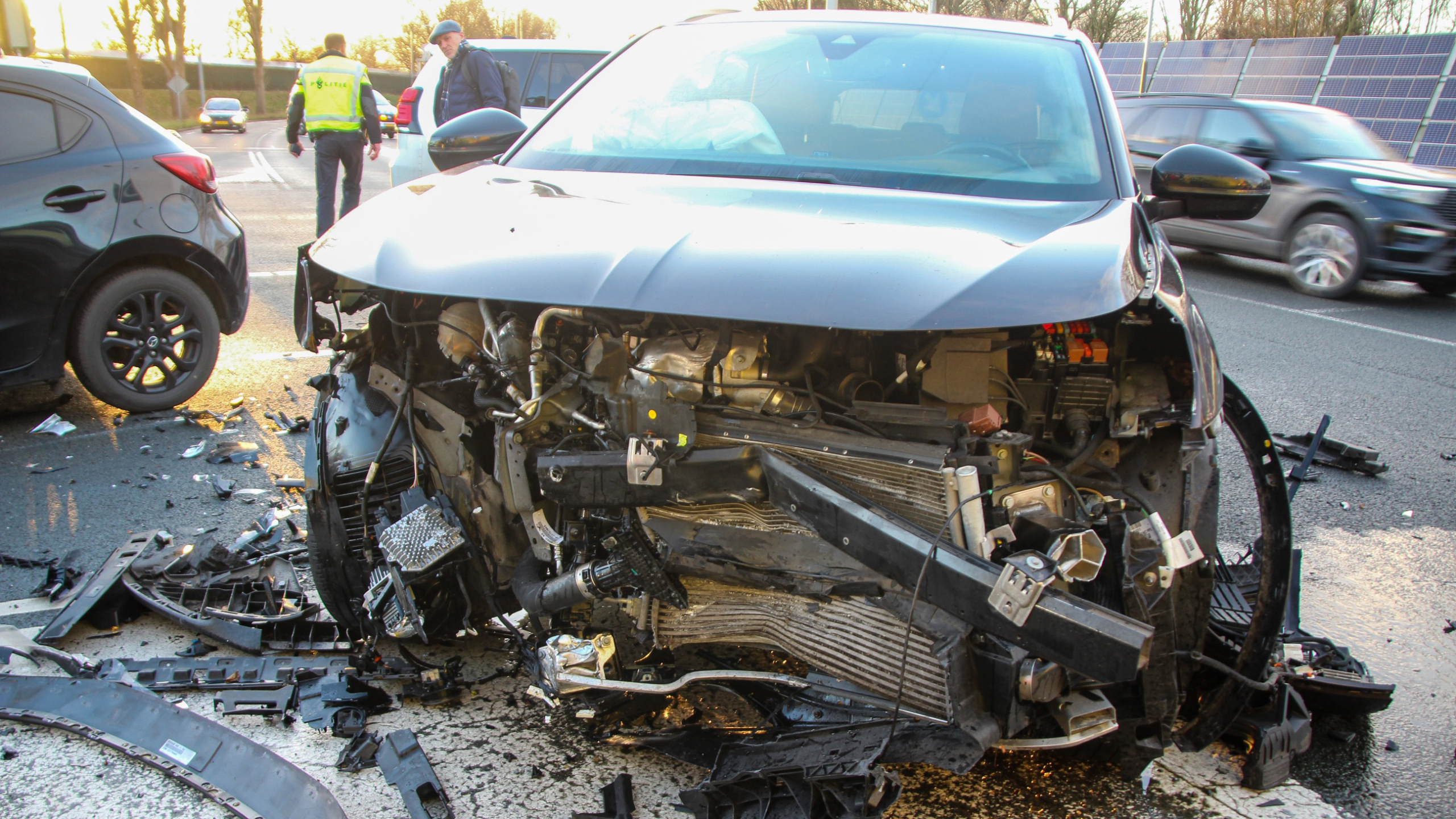 Politie- en ambulances staan bij een kruispunt met verkeerslicht; mensen in uniform overleggen.