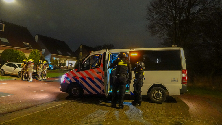 Vier politieagenten in oproeruitrusting staan 's nachts in een smalle straat.