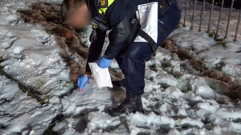 Brandweerlieden blussen 's nachts een brand in een zwarte auto, omringd door schuim en water op de grond.