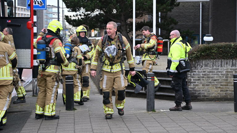 Brandweerwagens naast een zebrapad met verkeerskegels op de weg, omgeven door automobilisten en voetgangers.