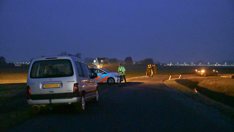 Auto gekanteld in een sloot langs een landelijke weg.