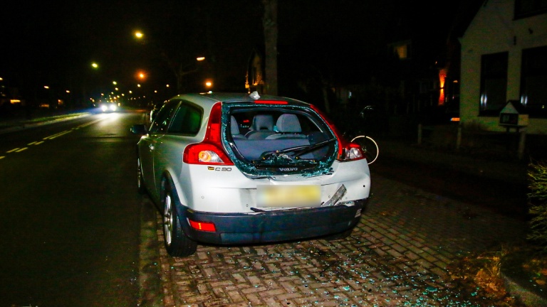 Auto-ongeluk in een woonwijk 's avonds, met twee voertuigen tegen elkaar, glas op de grond en politie-aanwezigheid.