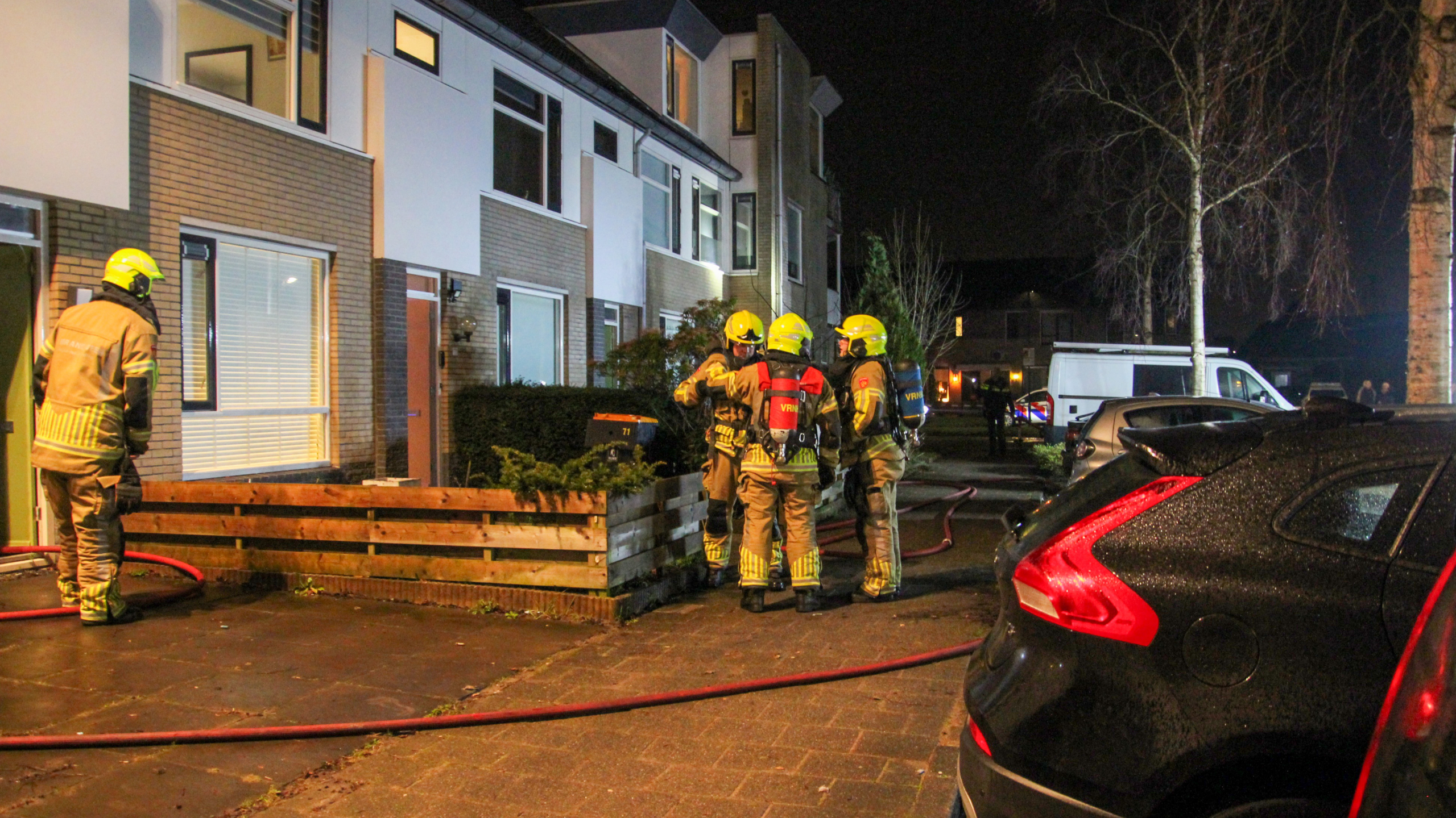 Rook komt uit het dak van een rijtjeshuis onder een donkere hemel.