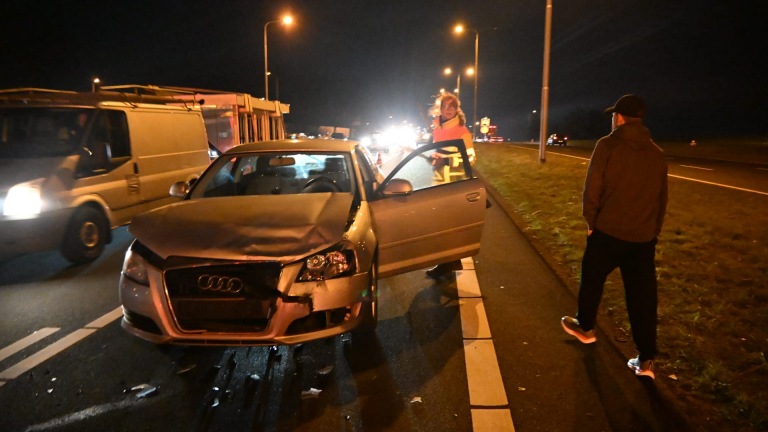 Verkeersopstopping op de snelweg 's nachts met politieauto en verkeerskegels die een rijstrook afsluiten.