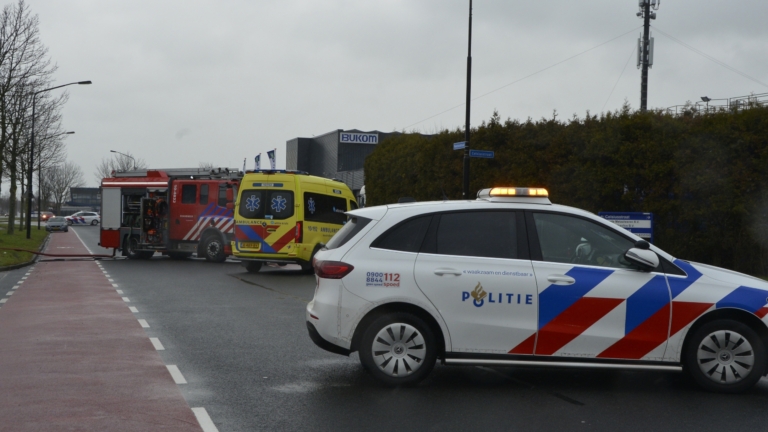Brandweerlieden blussen een motorbrand van een beschadigde auto met brandweeruitrusting en -slangen.