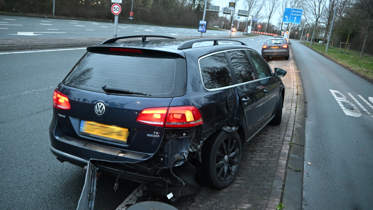 Verkeersongeval op kruispunt met politieauto en meerdere betrokken auto's op een regenachtige dag.