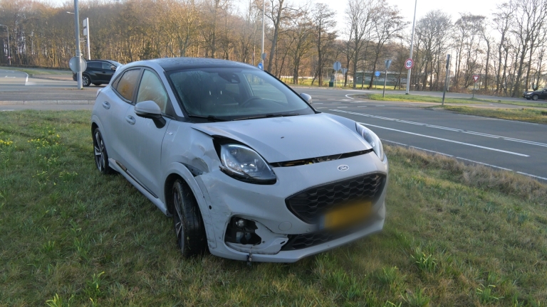 Politieagenten staan naast meerdere politievoertuigen langs de weg, met een groot verkiezingsbord op de achtergrond.