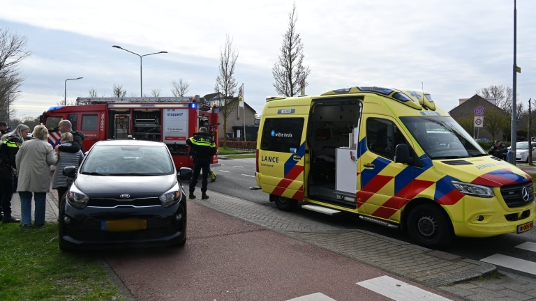 Hulpverleningsvoertuigen en mensen verzamelen zich bij een ongevalslocatie voor een gebouw.