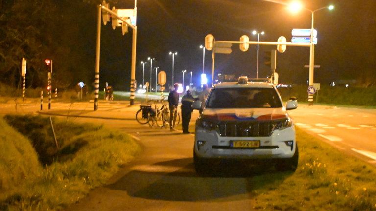 Een ambulance en een politiewagen bij een kruispunt met verkeerslichten 's nachts.