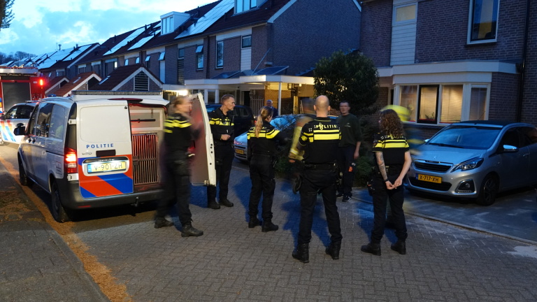 Politiemotor en agent op straat tijdens een avondlijke situatie met publiek en een brandweerwagen op de achtergrond.