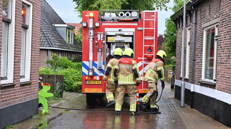 Verbrande fiets op een natte bakstenen straat, met zichtbare schade aan het frame en de wielen.