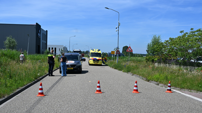 Grijze bestelwagen met aanzienlijke deuken aan de zijkant en een kapotte zijspiegel, geparkeerd op een weg.