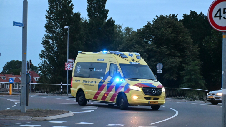 Twee politieauto's staan geparkeerd op een weg bij een kruispunt in een woonwijk.