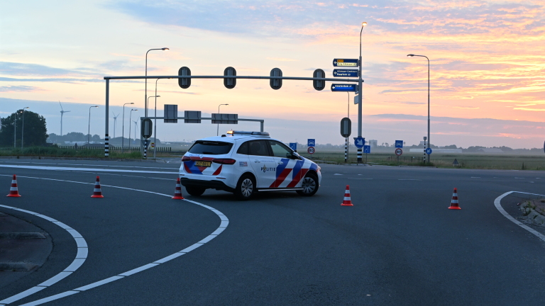 Een auto met ernstige schade aan de voorkant staat tegen een lantaarnpaal langs de weg.