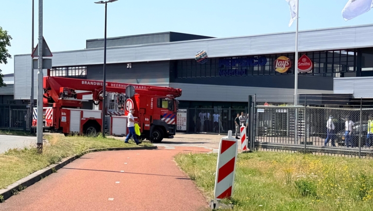 Een brandweerwagen staat geparkeerd buiten bij een gebouw met het logo van PepsiCo Nederland.