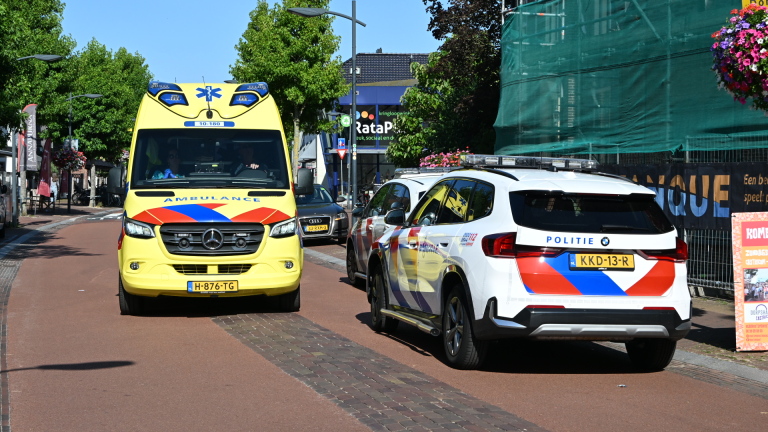 Ambulance en politieauto op een dorpsstraat, met de ambulance frontaal in beeld en de politieauto ernaast geparkeerd